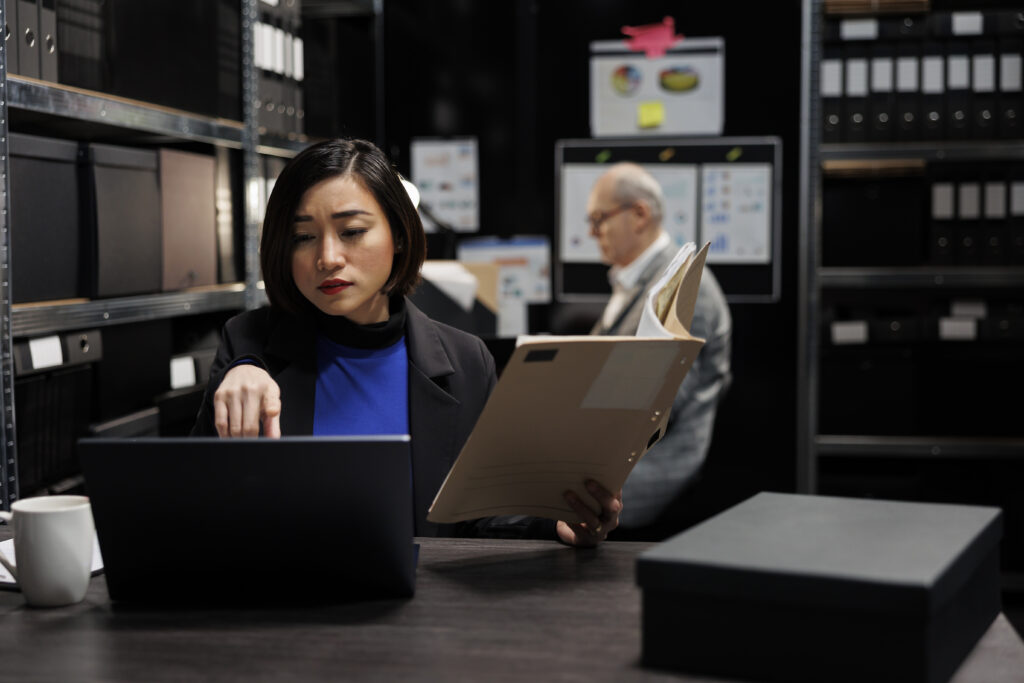 mulher asiátia segurando um tablet enquanto olha para um computador a sua frente - imagem para o blog: adições e exclusões ao lucro real