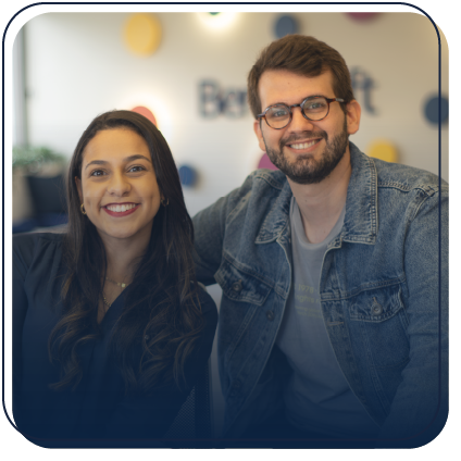 Dois funcionários da Bernhoeft (um homem a direita e uma mulher a esquerda) sorrindo e olhando para a câmera.