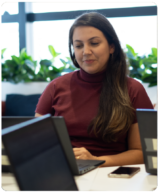 Funcionária Bernhoeft trabalhando em frente a um computador. Ela veste uma camisa vermelha escura.